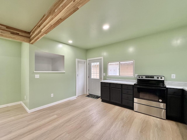 kitchen featuring electric range, light hardwood / wood-style floors, and beamed ceiling