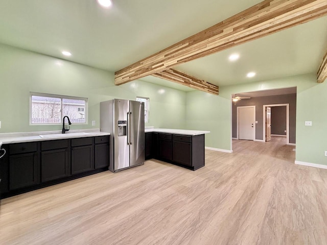 kitchen featuring beam ceiling, ceiling fan, sink, stainless steel refrigerator with ice dispenser, and light hardwood / wood-style floors