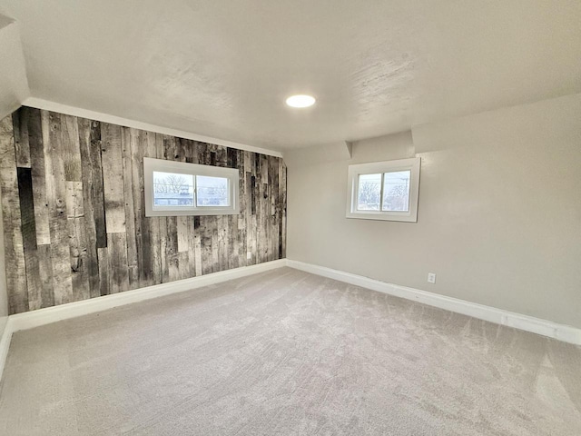 unfurnished room featuring carpet and wooden walls