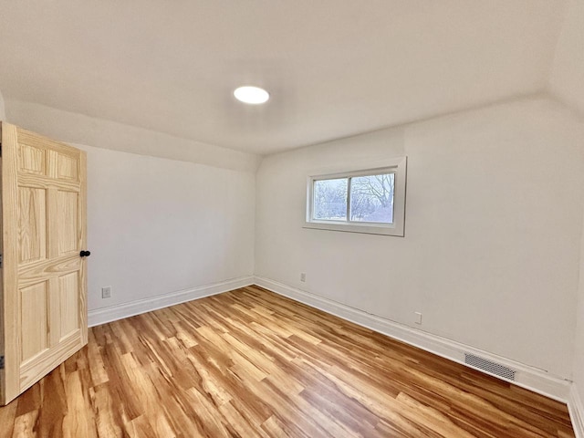 empty room with hardwood / wood-style floors and vaulted ceiling