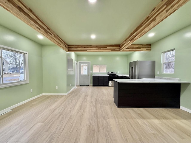 kitchen with beamed ceiling, light hardwood / wood-style floors, kitchen peninsula, and appliances with stainless steel finishes