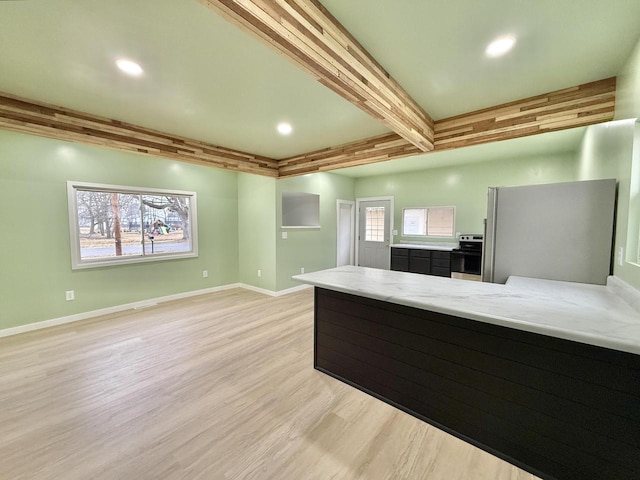 kitchen with light hardwood / wood-style flooring, light stone countertops, appliances with stainless steel finishes, beam ceiling, and kitchen peninsula