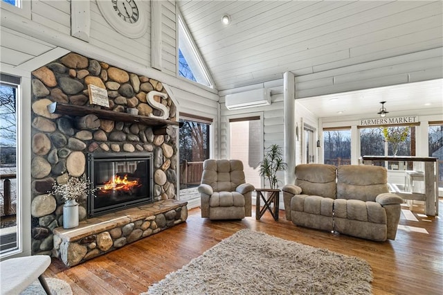 living room with an AC wall unit, a stone fireplace, high vaulted ceiling, and hardwood / wood-style flooring