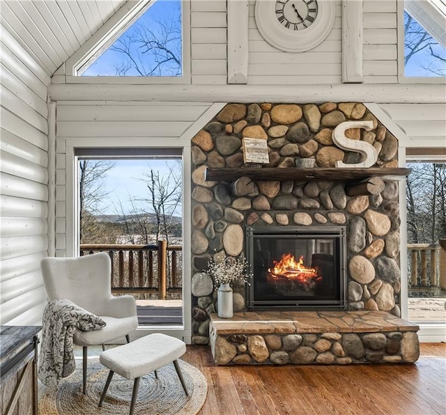 sitting room featuring hardwood / wood-style floors, high vaulted ceiling, a fireplace, and log walls