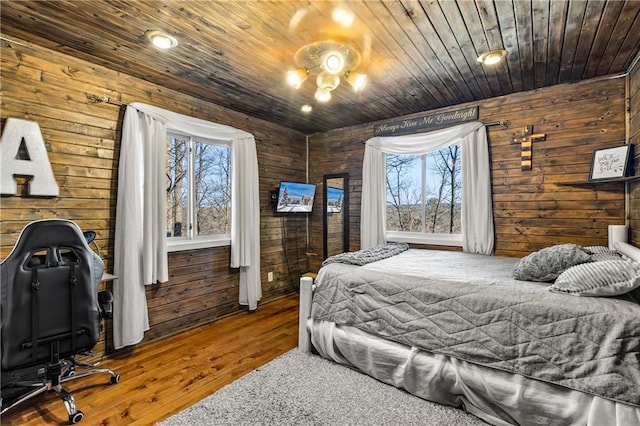 carpeted bedroom with multiple windows, wooden ceiling, and wood walls