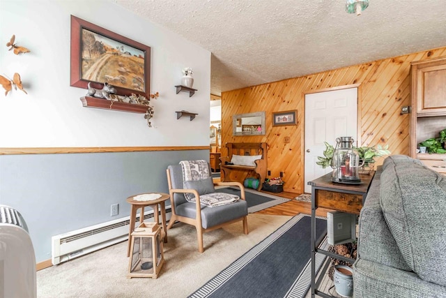 living area with a textured ceiling, carpet floors, baseboard heating, and wooden walls