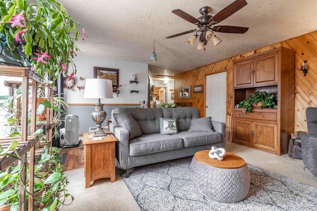 carpeted living room featuring a textured ceiling, ceiling fan, and wooden walls