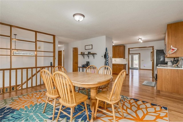 dining space with light wood-type flooring and a textured ceiling