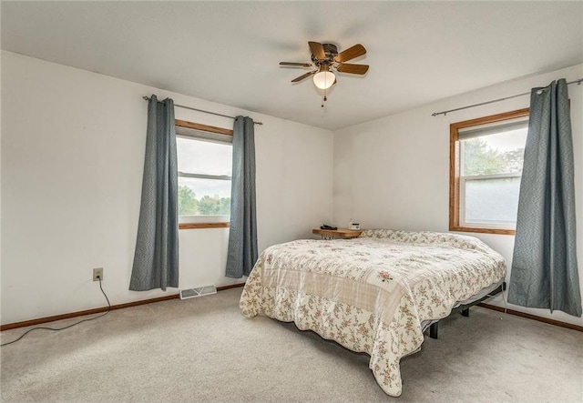 carpeted bedroom with multiple windows and ceiling fan