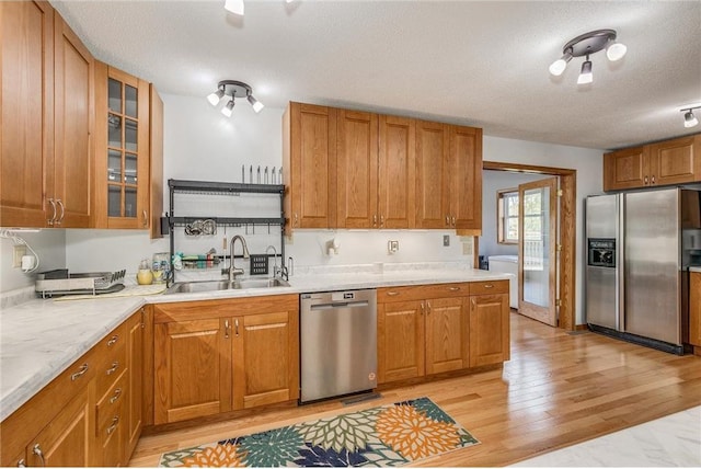 kitchen with sink, light hardwood / wood-style flooring, a textured ceiling, and appliances with stainless steel finishes