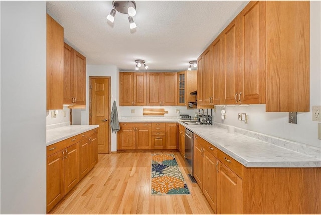 kitchen with sink, dishwasher, a textured ceiling, and light wood-type flooring