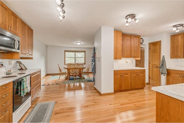 kitchen with a textured ceiling, electric range, and light hardwood / wood-style floors