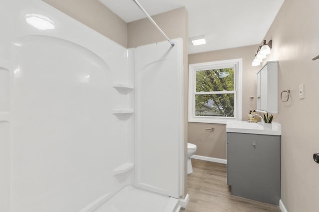 bathroom with a shower, hardwood / wood-style floors, vanity, and toilet