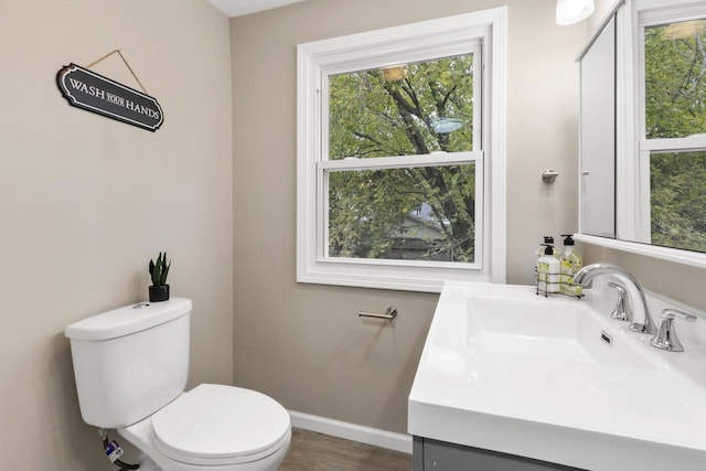 bathroom featuring vanity, a healthy amount of sunlight, and toilet