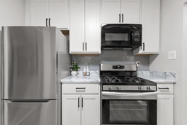 kitchen featuring white cabinets, appliances with stainless steel finishes, decorative backsplash, and light stone countertops