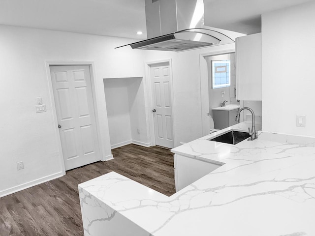 kitchen featuring light stone countertops, sink, dark hardwood / wood-style flooring, island exhaust hood, and white cabinets