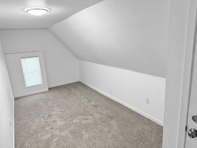 bonus room with carpet, a textured ceiling, and vaulted ceiling