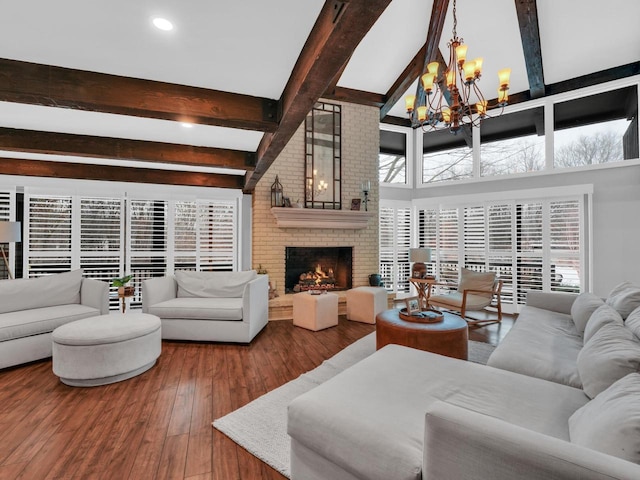 living room with an inviting chandelier, a towering ceiling, a fireplace, beamed ceiling, and wood-type flooring