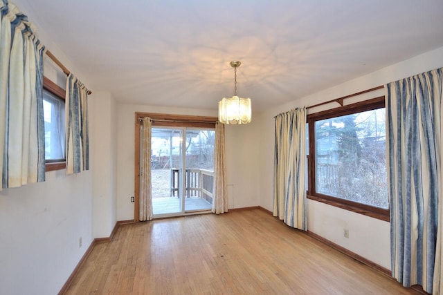 empty room with a notable chandelier and light wood-type flooring