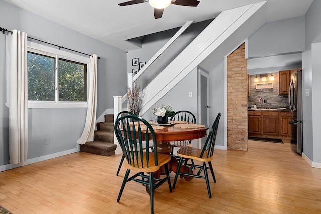 dining space with ceiling fan, light wood-type flooring, sink, and lofted ceiling