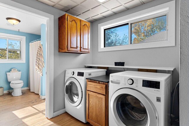 clothes washing area with washing machine and dryer and light hardwood / wood-style flooring