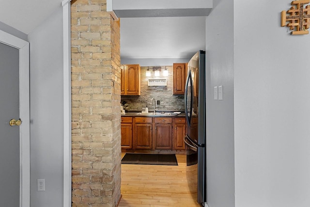 kitchen with decorative backsplash, stainless steel fridge, light hardwood / wood-style flooring, and sink