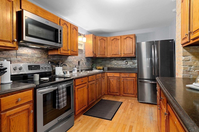 kitchen featuring decorative backsplash, sink, light wood-type flooring, and appliances with stainless steel finishes