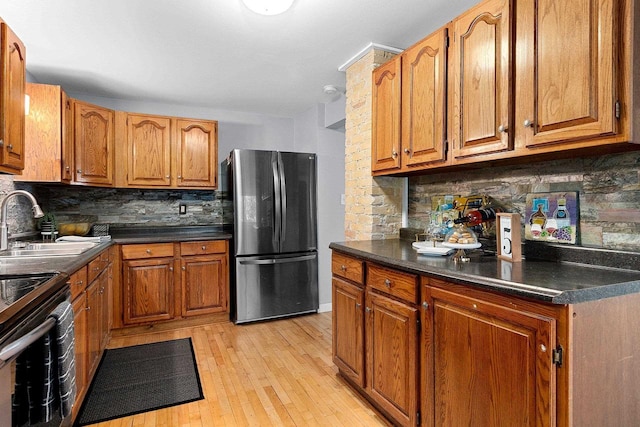 kitchen featuring range with electric cooktop, sink, tasteful backsplash, light hardwood / wood-style flooring, and stainless steel fridge