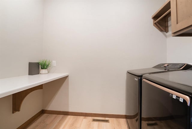 washroom featuring cabinets, washer and dryer, and light wood-type flooring