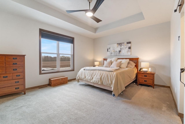 bedroom featuring carpet floors, a raised ceiling, and ceiling fan