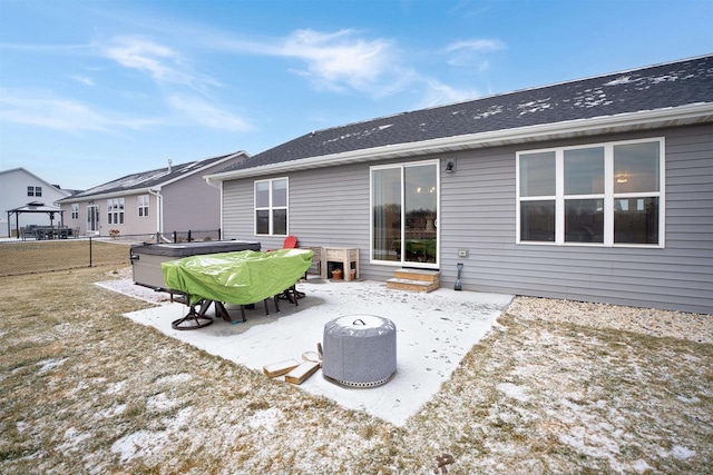 snow covered back of property featuring a patio area and a hot tub