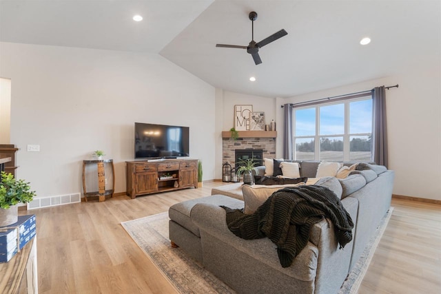 living room with ceiling fan, a fireplace, vaulted ceiling, and light hardwood / wood-style flooring