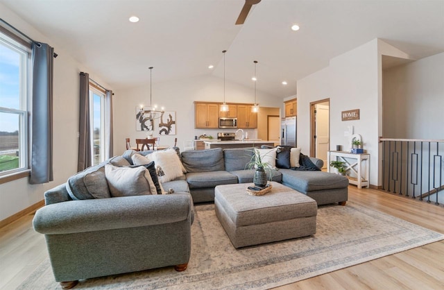 living room with light hardwood / wood-style flooring, ceiling fan with notable chandelier, vaulted ceiling, and sink