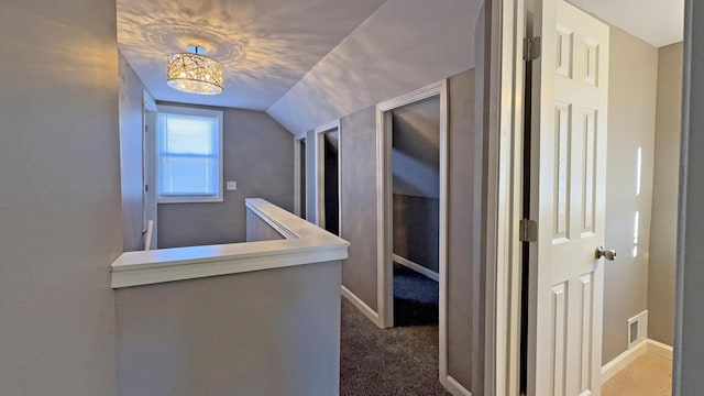 hallway with carpet flooring and vaulted ceiling