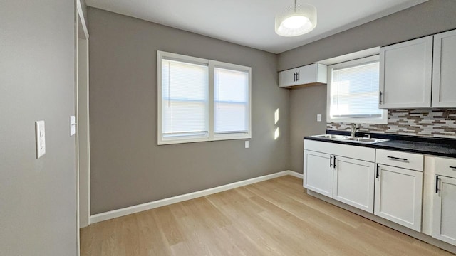 kitchen with white cabinetry, decorative backsplash, sink, and light hardwood / wood-style flooring