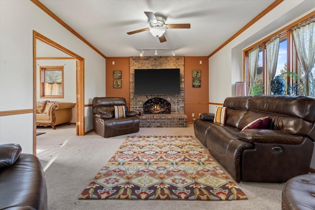 living room featuring ceiling fan, rail lighting, light colored carpet, a fireplace, and ornamental molding