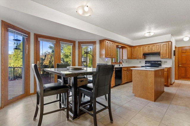 kitchen featuring black appliances, sink, light tile patterned floors, a textured ceiling, and a kitchen island