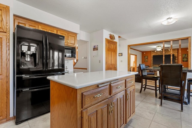 kitchen with light tile patterned floors, a kitchen island, black appliances, and a textured ceiling