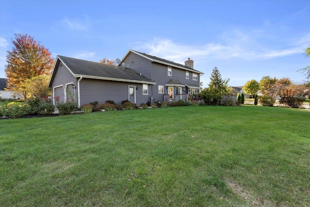 rear view of house with a garage and a yard