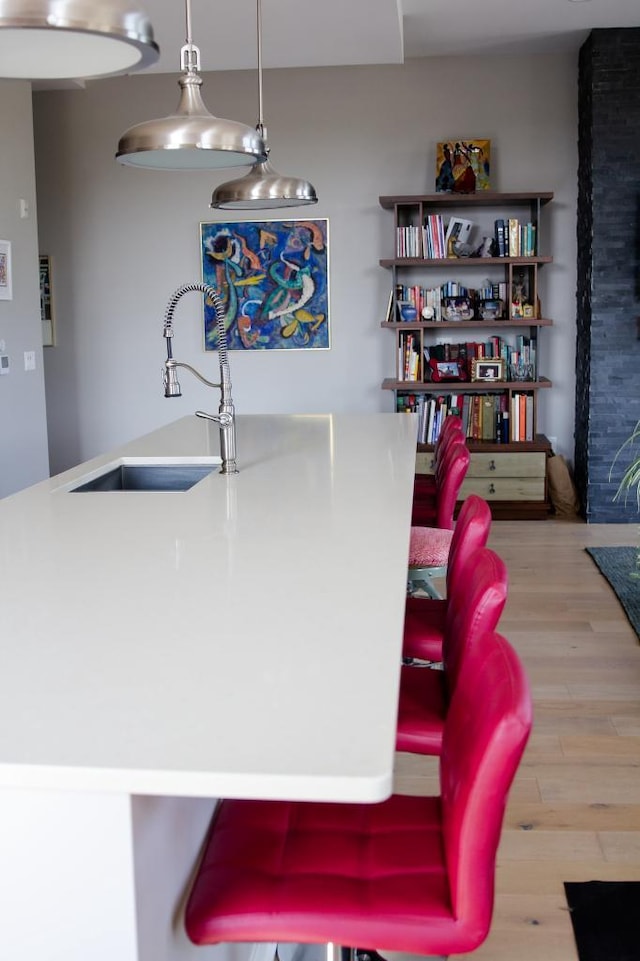 interior space featuring pendant lighting, light hardwood / wood-style floors, and sink