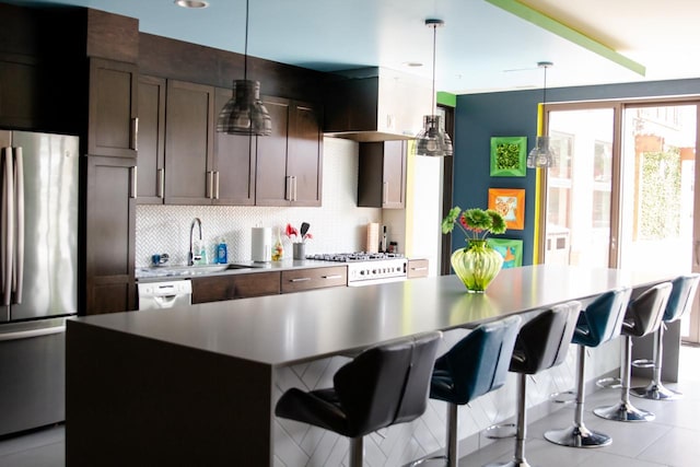 kitchen featuring decorative backsplash, stainless steel refrigerator, hanging light fixtures, and a kitchen island