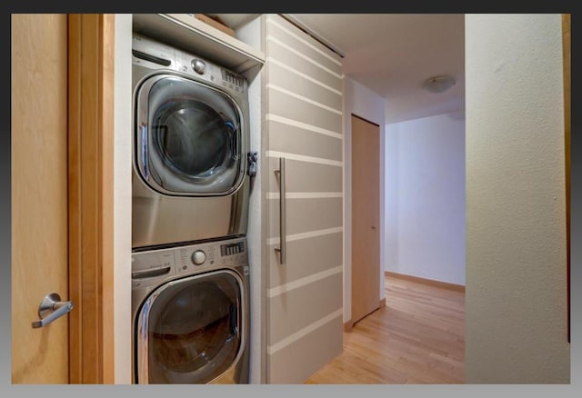 laundry area featuring light hardwood / wood-style flooring and stacked washer and clothes dryer