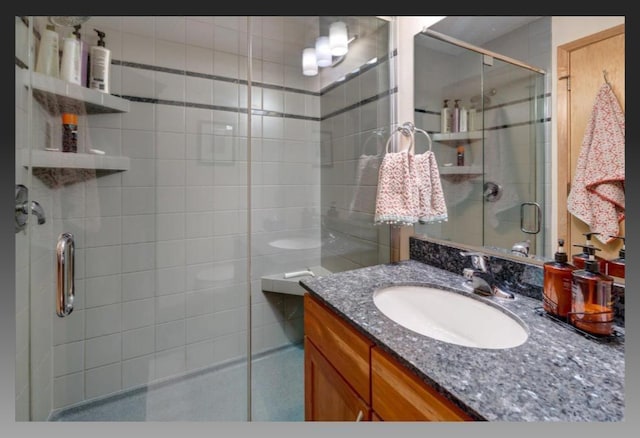 bathroom featuring a shower with door and vanity