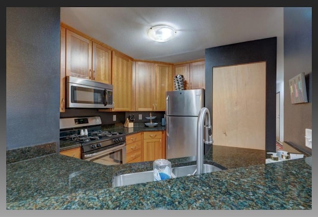 kitchen featuring appliances with stainless steel finishes, sink, and dark stone counters