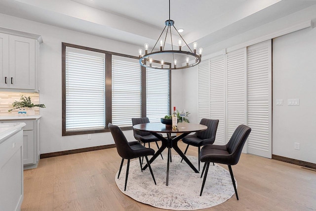 dining area with light hardwood / wood-style floors and an inviting chandelier