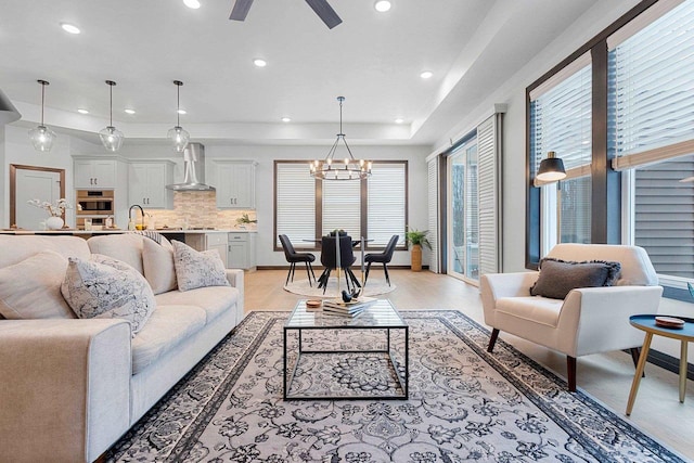 living room featuring sink and ceiling fan with notable chandelier