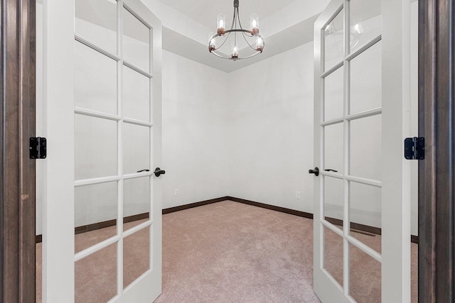 spacious closet with light carpet, french doors, and a notable chandelier