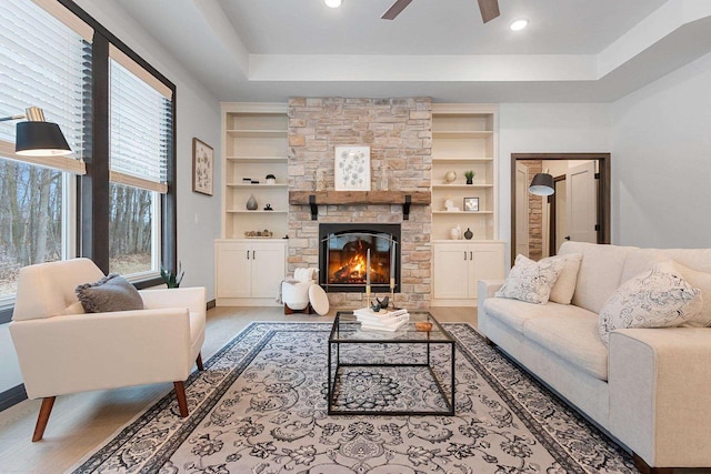 living room featuring a fireplace, built in shelves, plenty of natural light, and ceiling fan