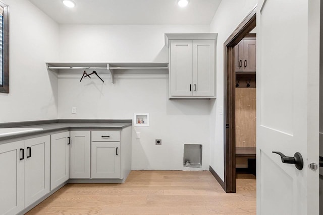 laundry area with hookup for an electric dryer, hookup for a washing machine, light hardwood / wood-style floors, and cabinets