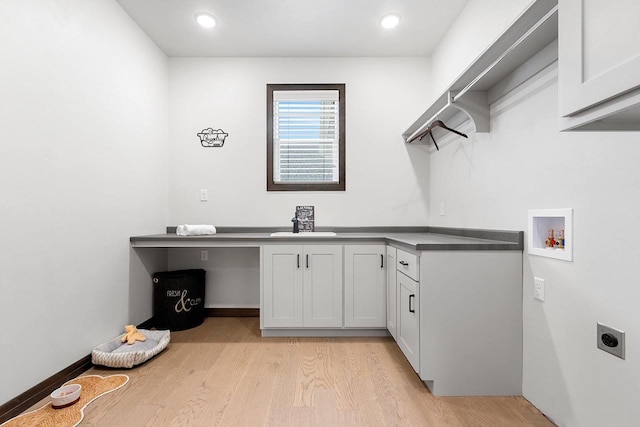 laundry room featuring cabinets, sink, hookup for a washing machine, light hardwood / wood-style flooring, and hookup for an electric dryer